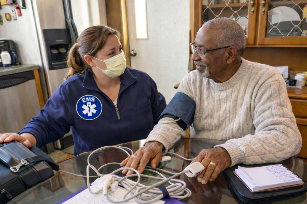 Female paramedic conducting home health visit with elderly Black patient in rural community setting. AI-generated image